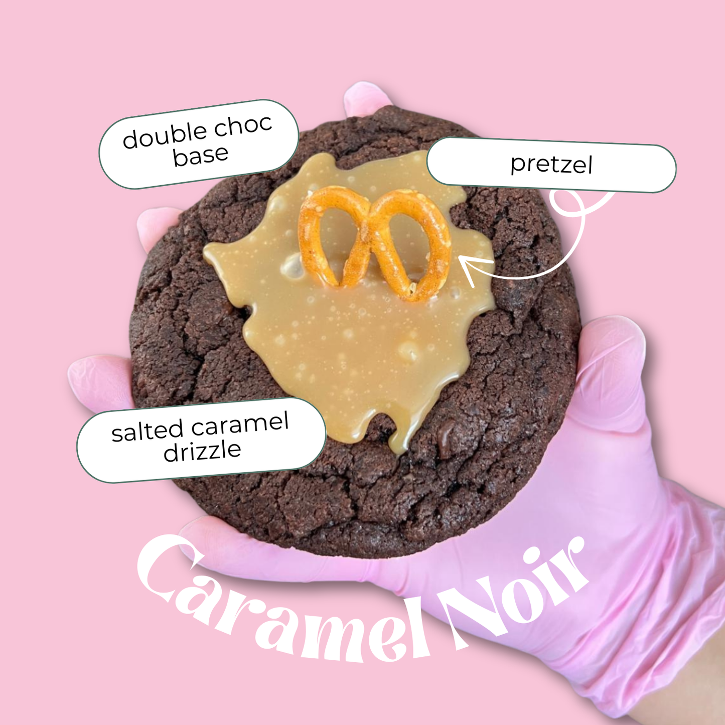 Chocolate cookie with salted caramel drizzle and pretzel piece, labeled 'Caramel Noir' on a pink background.